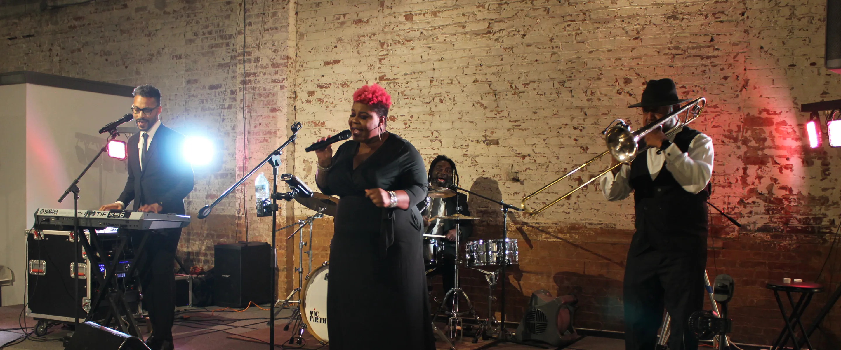 three people performing music playing keyboard, singing, trumpet