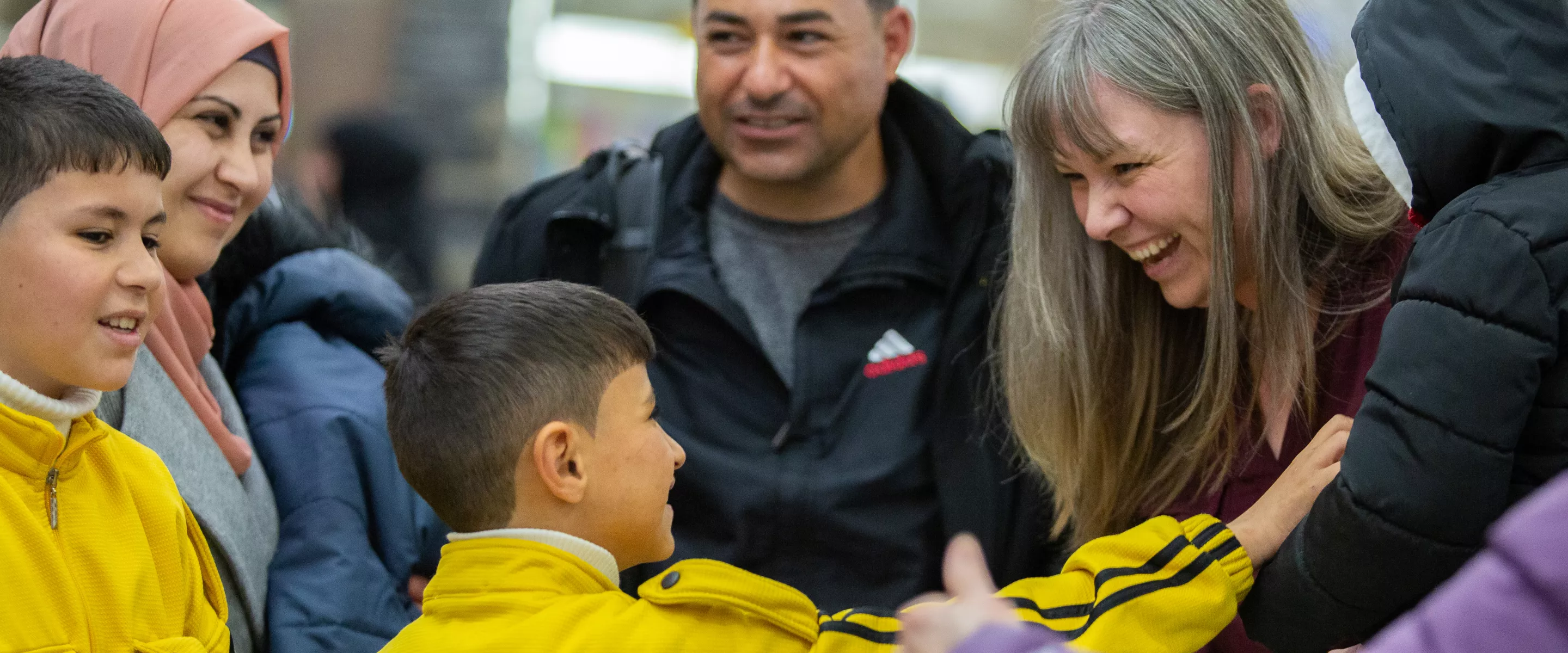 a family of refugees is greeted at the airport by their sponsors