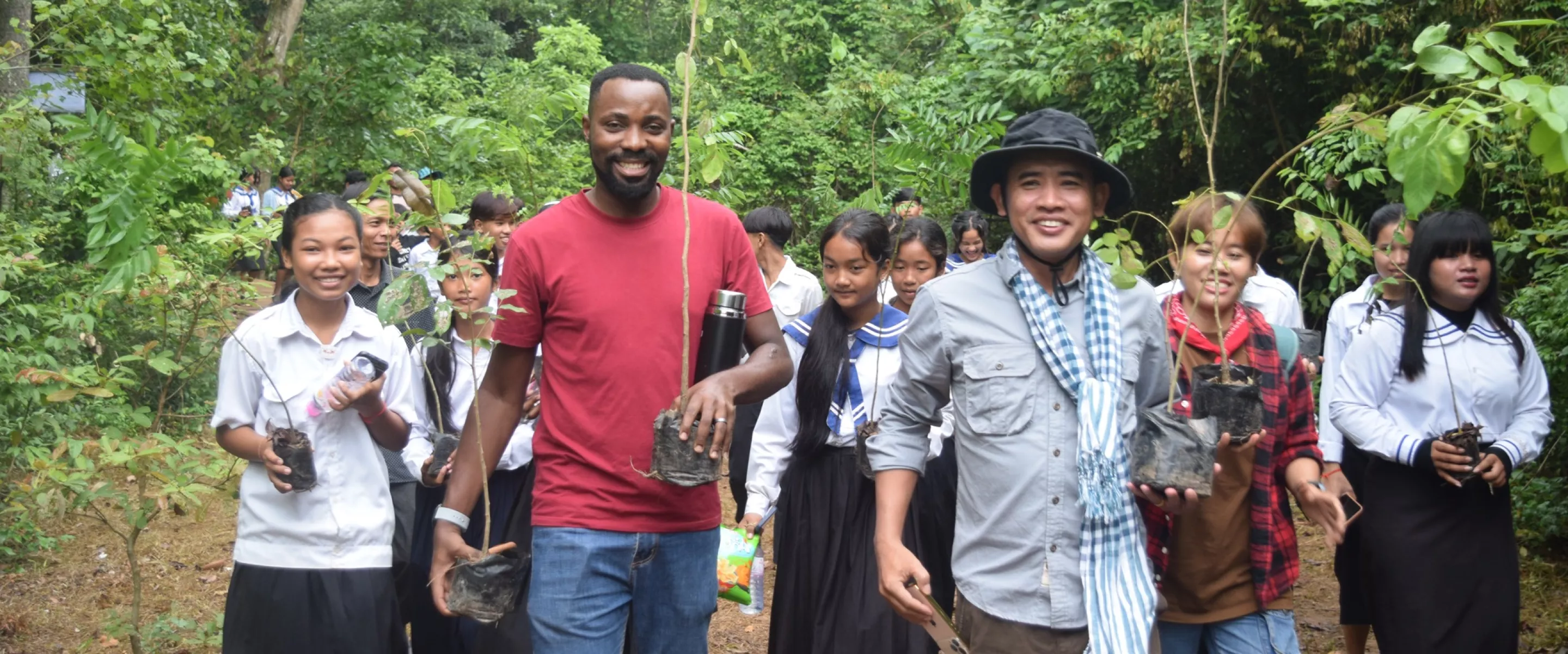 MCC Cambodia staff and students from a local school carry saplings to plant in a deforested area in the Monks Community Forest in northwest Cambodia.