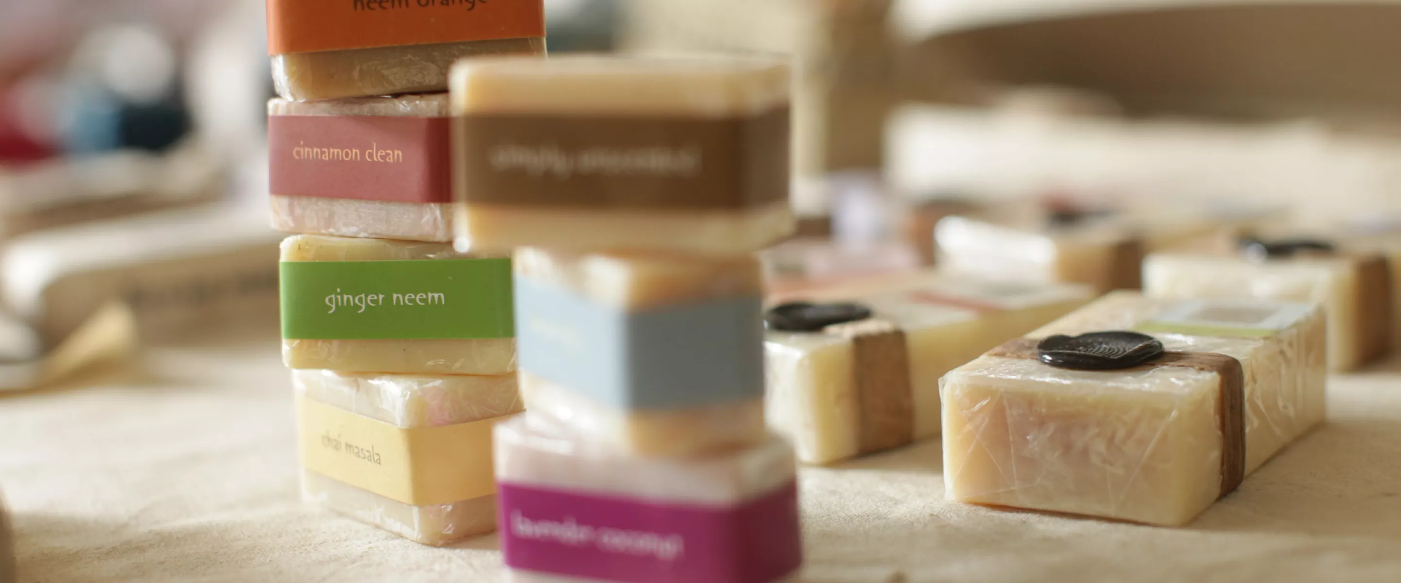 Bars of soap with different coloured labels are stacked one on top of the other while other soap sits flat in the background.