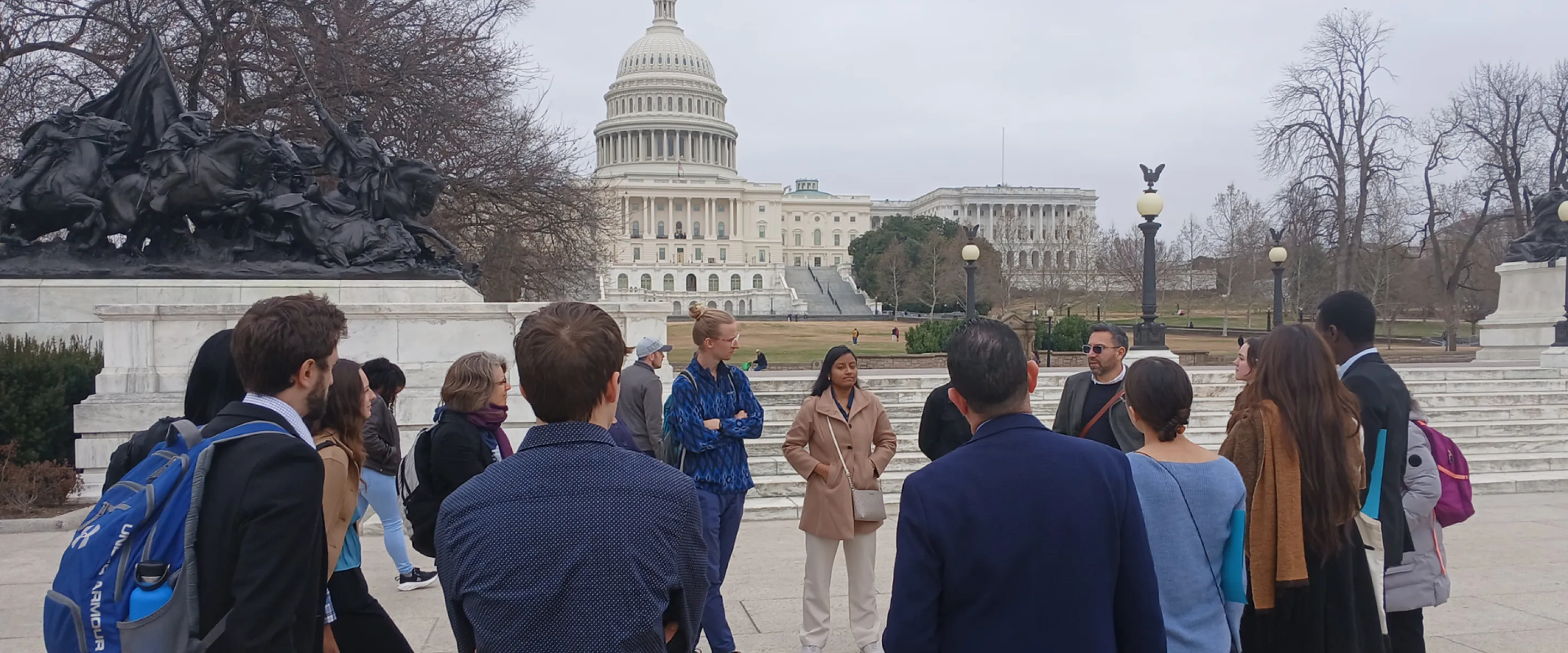 Group of young adults standing in a circle in front of the capital building