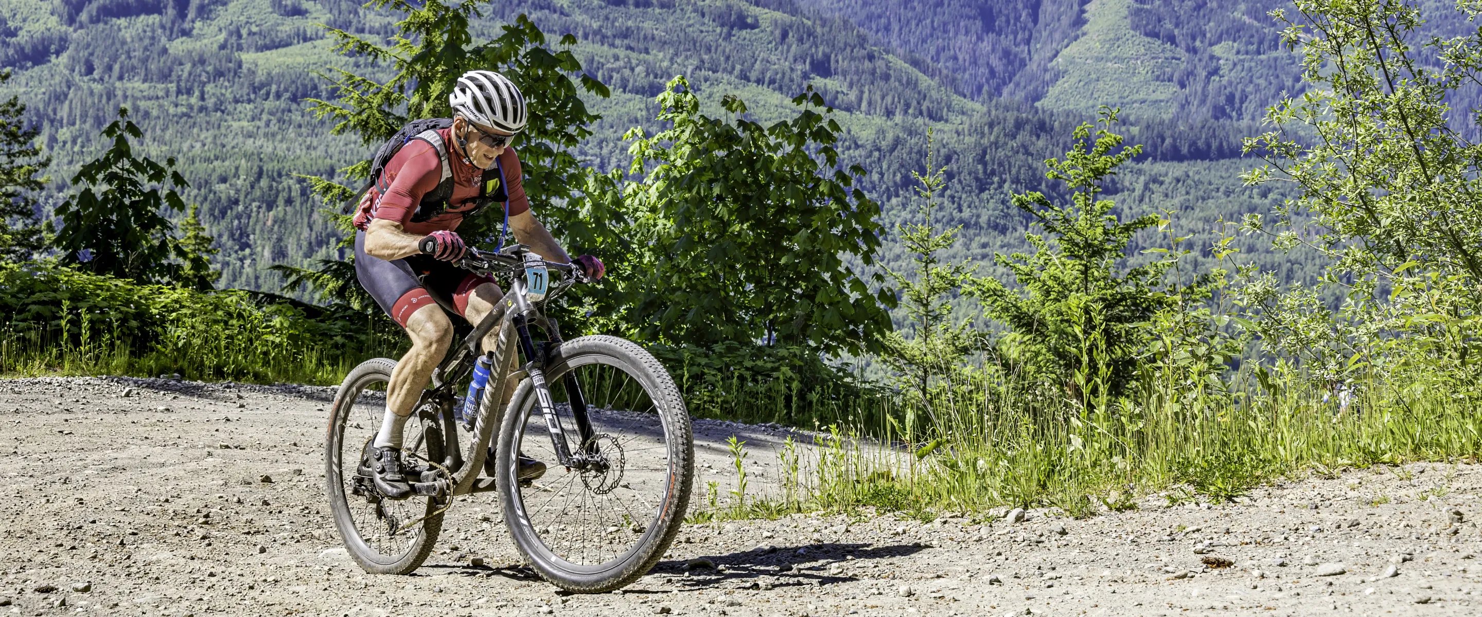 A man cycles uphill with mountains in the background