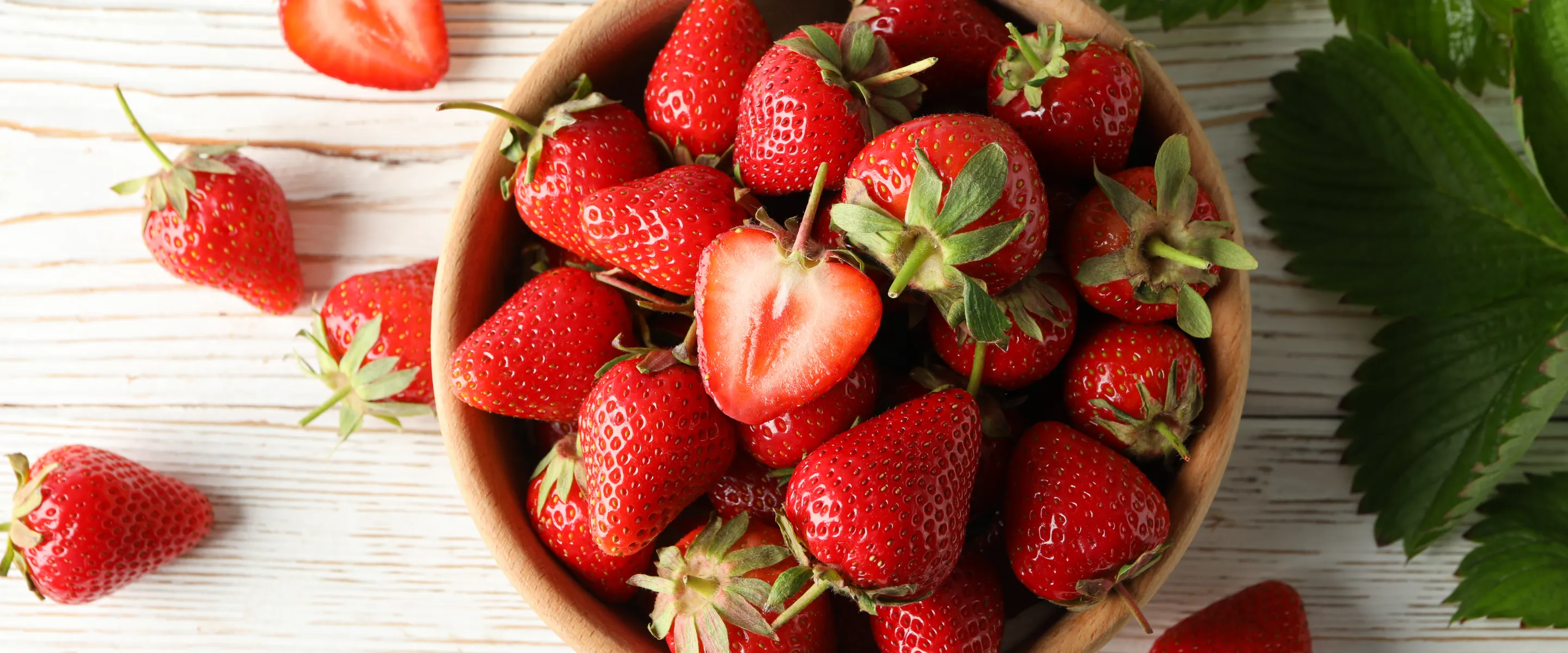 A bowl of strawberries from above with a bright background.