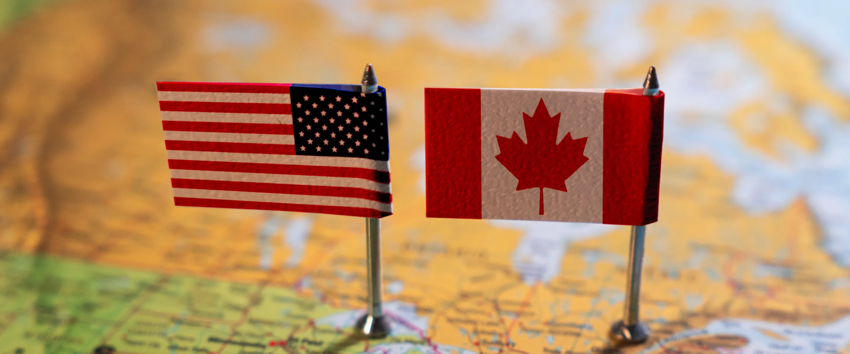 A map of part of the US and with two small American and Canadian flags sitting on top of it.