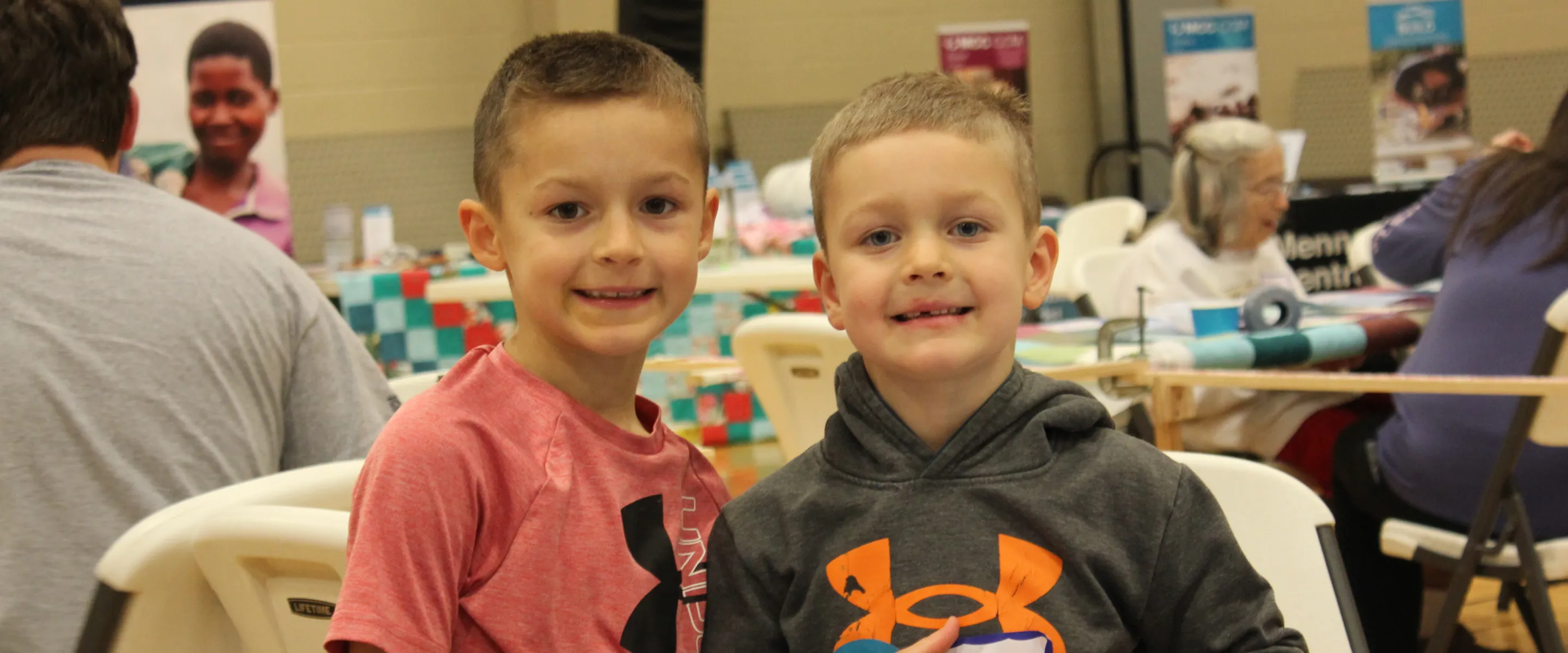 two boys stand by quilt