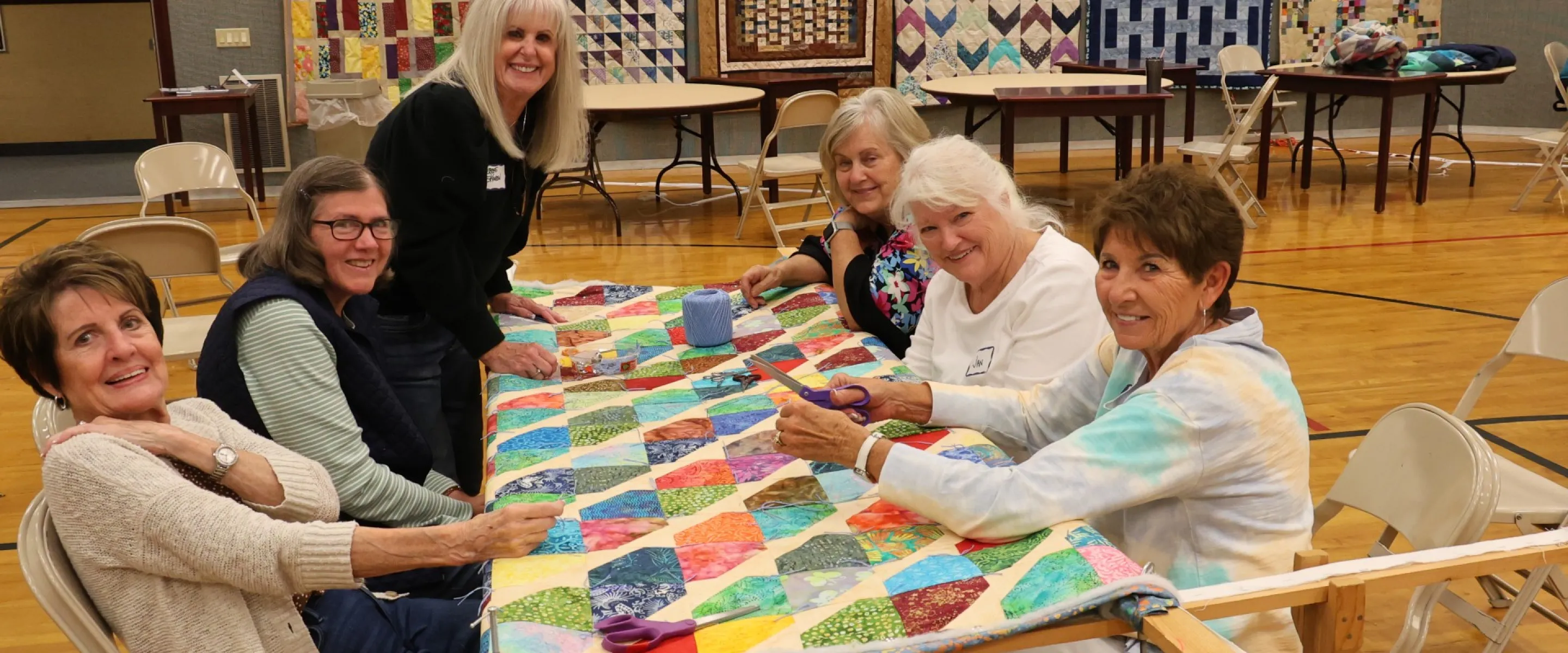 group of women sitting around a comforter
