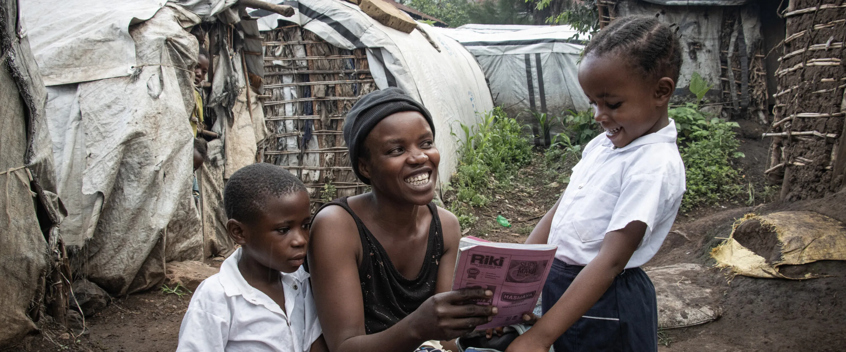 War-displaced Bahati Kamara Chance, center, checks her daughter Bulonza Amina’s notebook before Bulonza and Nelly Kabumba, left, go off to school. Chance continually checks her daughter's grades.