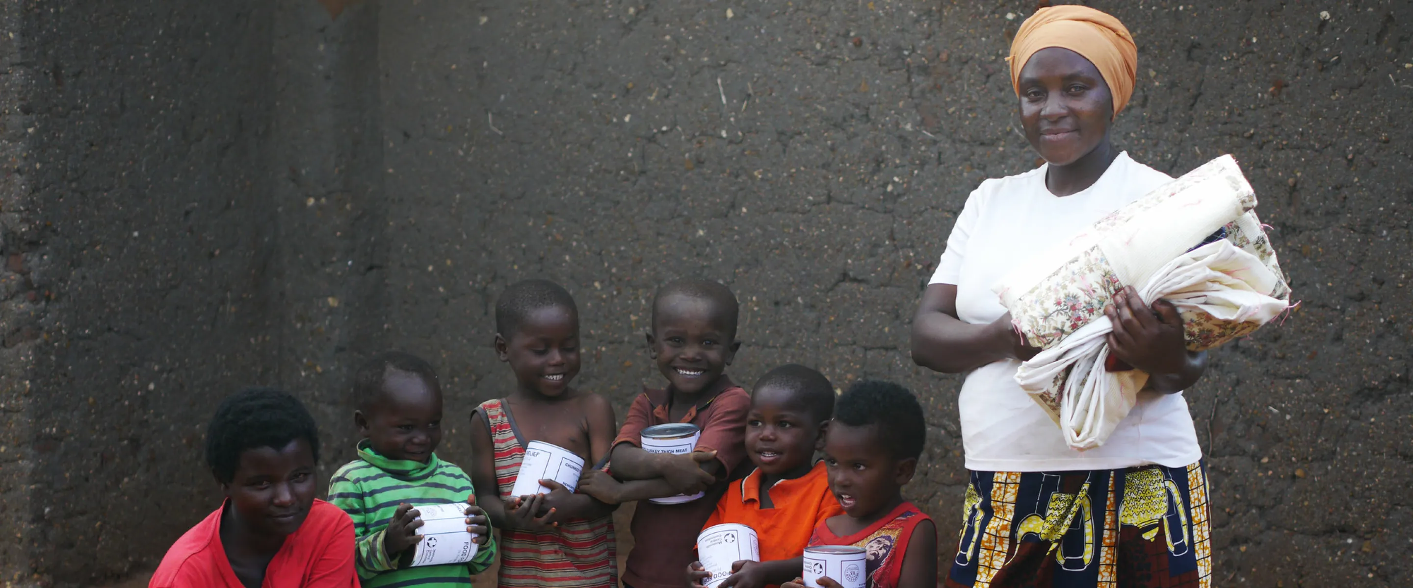 Nizigama Bestide, who lives in Dzaleka Refugee Camp in Malawi, stands with her children Ngurunziza Neema, Venist Neema, Press Neema, Gard Neema, Erie Neema, and Kabura Oneszima. The family is holdin