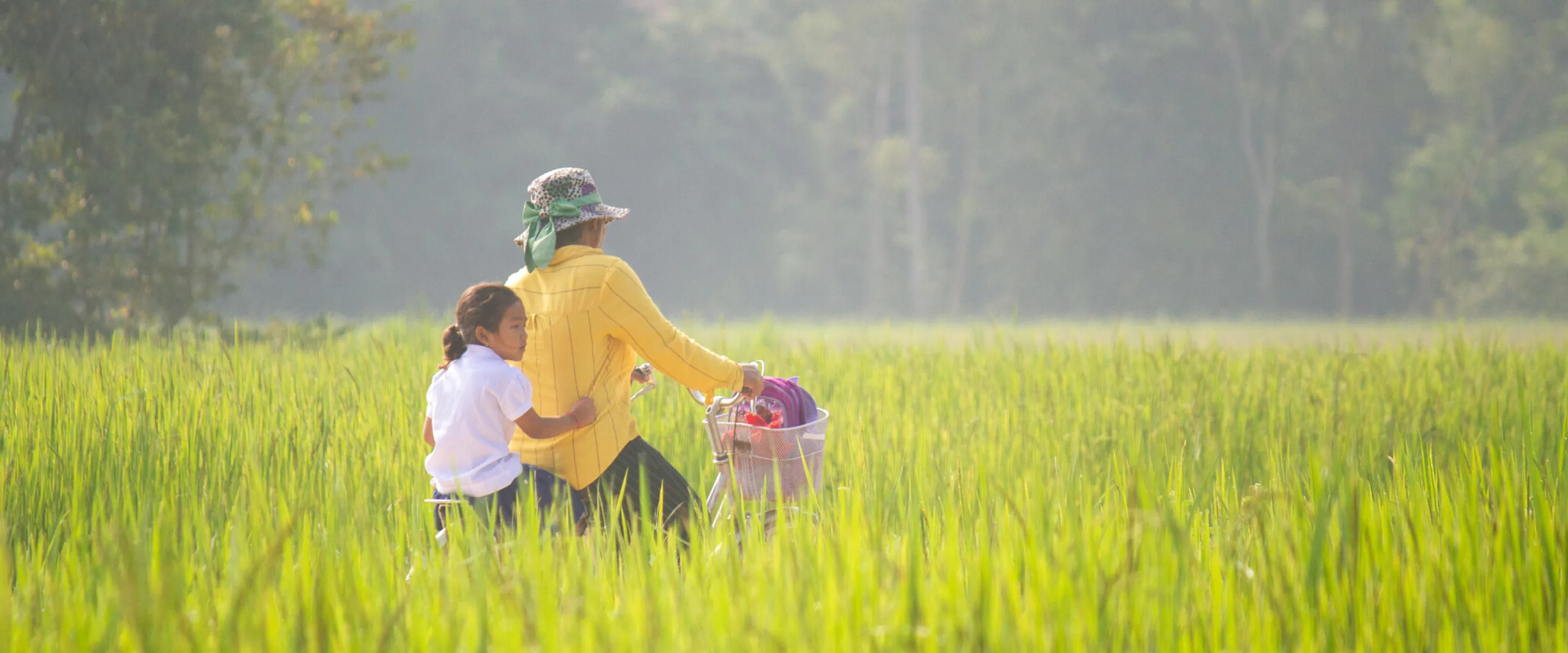 Tau Sreyneing rides a bike through rice fields with her daughter Tung Sreyneat riding behind in Mesang district, Cambodia. Bikes are one of the main forms of transportation in Cambodia, especially in