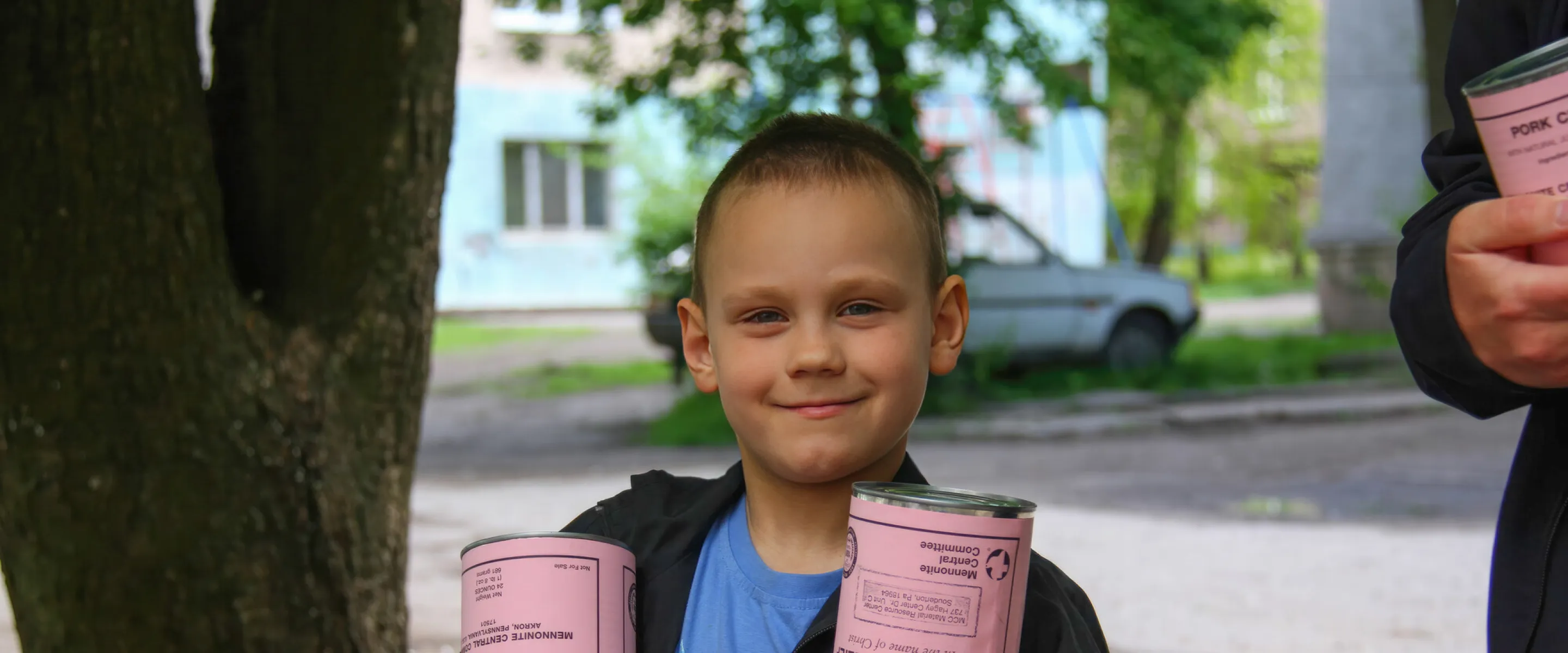 A boy* holds cans of meat he and his mother (not pictured) received from volunteers with MCC partner Association of Mennonite Brethren Churches of Ukraine (AMBCU). The canned meat was part of a distri