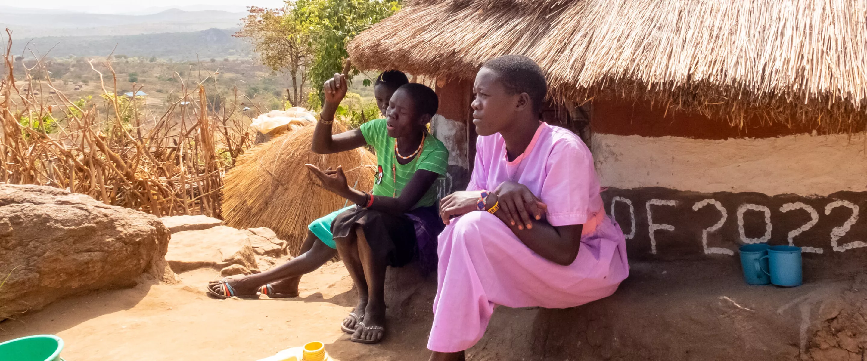 Evalin Ayollo (left), their mother Elizabeth Ariko, and Nicolina Napeyok, 16 (purple) at the family home on a hill above the village of Lokwakaromoe, Uganda.