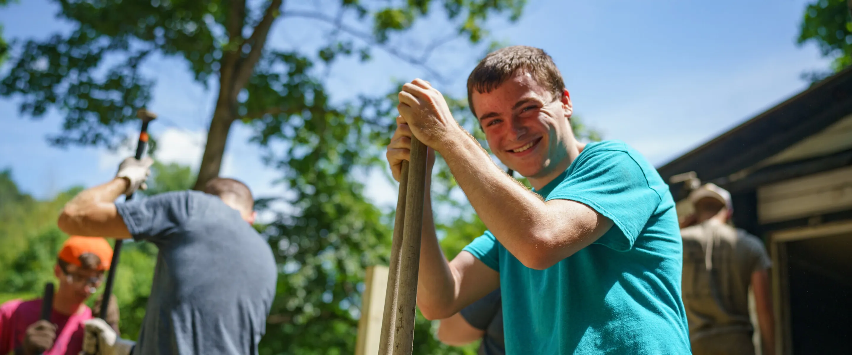 Micah Dodson, left, Appalachia Build staff, digs a hole for a post to support a wheelchair ramp in Kimball, West Virginia.