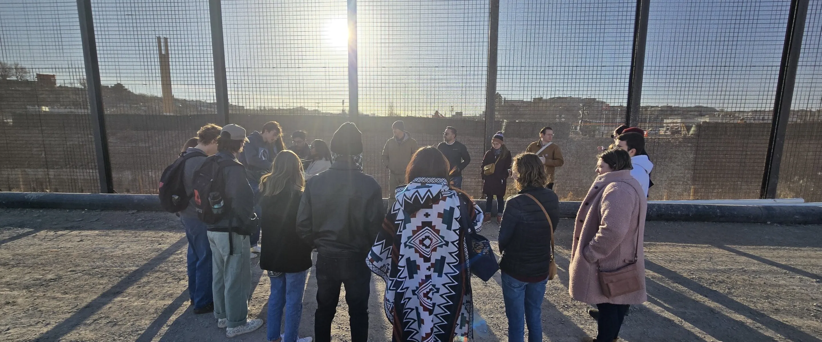 Saulo Padilla, MCC U.S. Migration Education Coordinator, speaks to MCC Borderlands Peace Camp participants in front of the U.S.-Mexico border wall in El Paso, Texas. The group lit a candle as a prayer