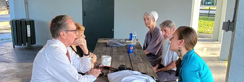 people sit at a picnic table for a meal