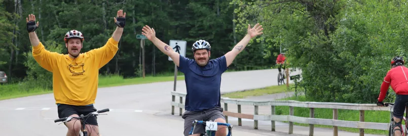 Two male cyclist in an open road with hands raised