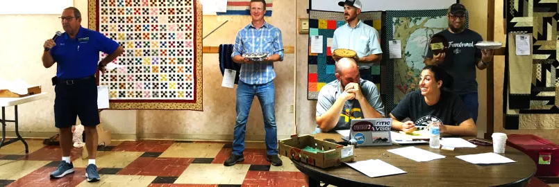 Men holding pies they made to be auctioned.