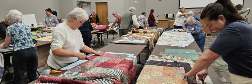 two women trim the edges of comforters 