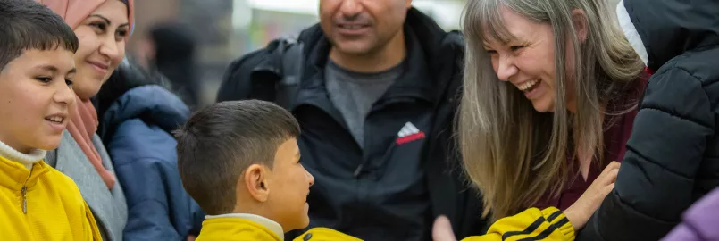 a family of refugees is greeted at the airport by their sponsors