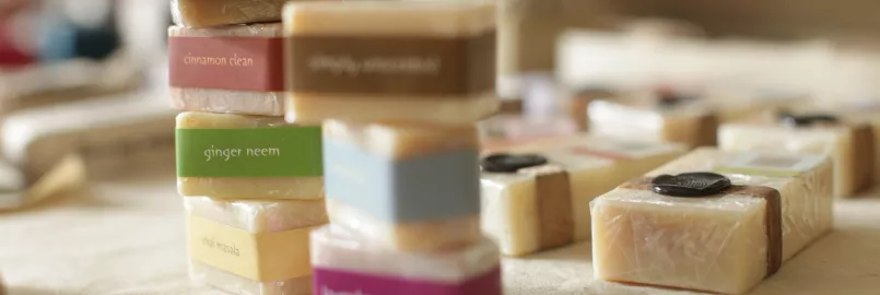 Bars of soap with different coloured labels are stacked one on top of the other while other soap sits flat in the background.
