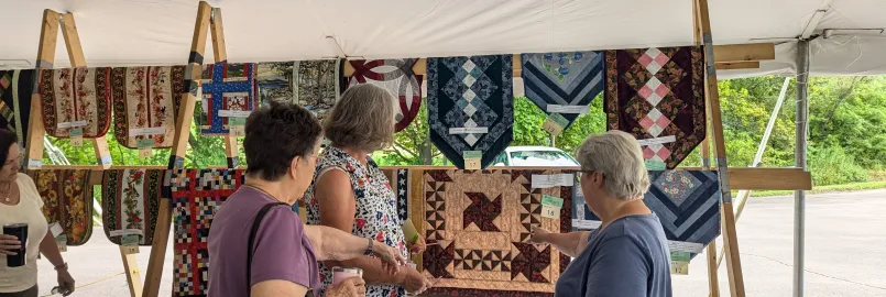 Women admiring quilts on a rack