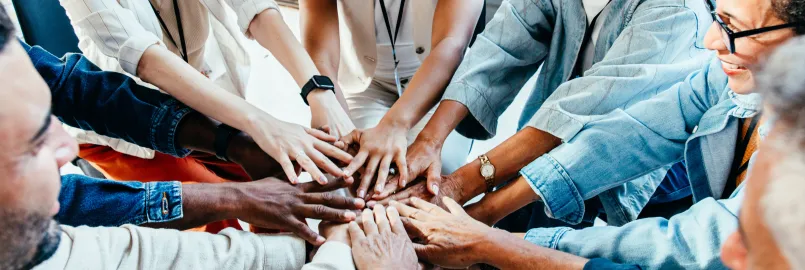 Individuals of varying age and race form a circle with their hands coming together in the centre.