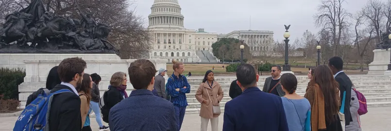 Group of young adults standing in a circle in front of the capital building