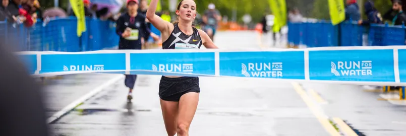 A female runner crossing the Run For Water finish line