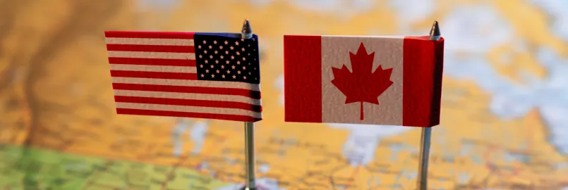 A map of part of the US and with two small American and Canadian flags sitting on top of it.