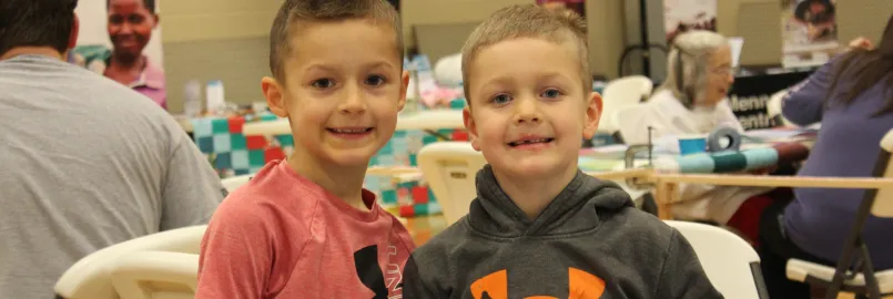 two boys stand by quilt