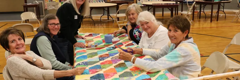 group of women sitting around a comforter