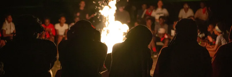 Four youth sit in front of campfire