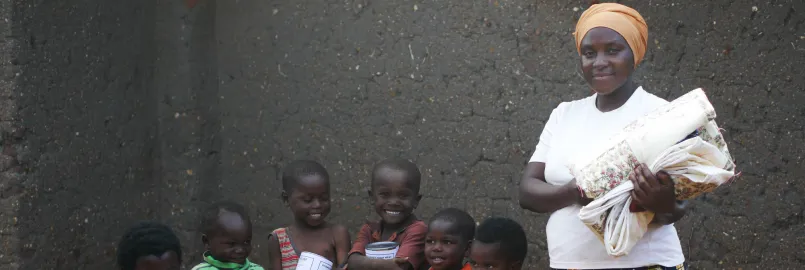 Nizigama Bestide, who lives in Dzaleka Refugee Camp in Malawi, stands with her children Ngurunziza Neema, Venist Neema, Press Neema, Gard Neema, Erie Neema, and Kabura Oneszima. The family is holdin