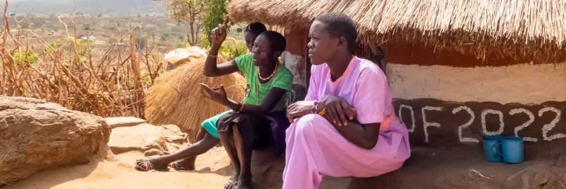 Evalin Ayollo (left), their mother Elizabeth Ariko, and Nicolina Napeyok, 16 (purple) at the family home on a hill above the village of Lokwakaromoe, Uganda.