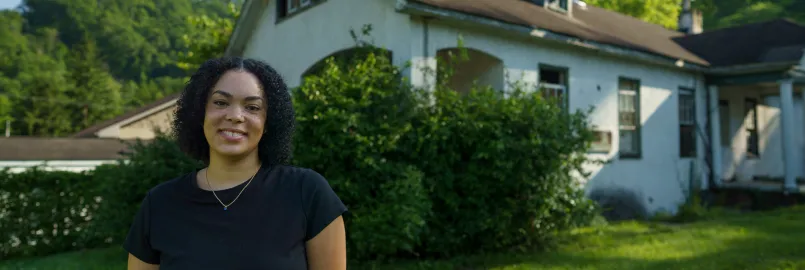 Tylah Cline, Dismukes Project Coordinator,  stands  in front of the Nurse‘s Home of the former Dismukes Hospital.