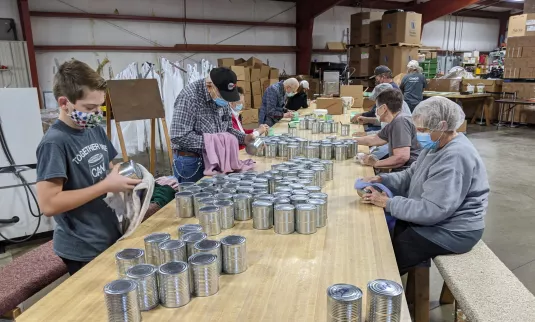 Groupe de bénévoles apposant des étiquettes sur des boîtes de conserve.