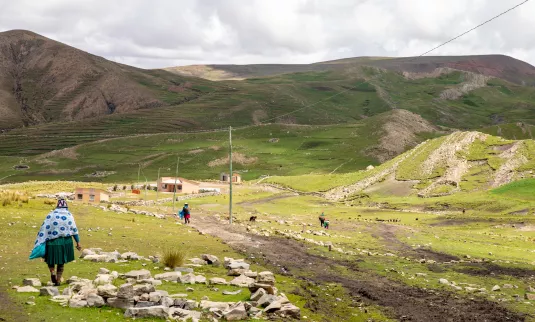 A woman walking towards a large hill in Bolivia
