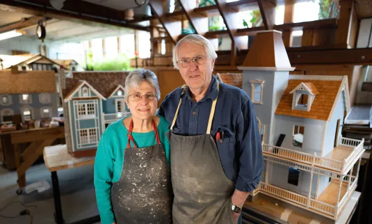 A man and woman standing in front of a room full of dollhouses