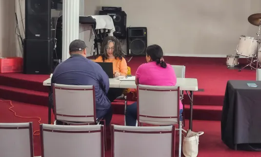 A couple sits at a table talking with a counselor.