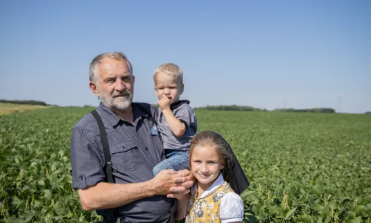 Grow Hope farmer Jerry Walder with two of his grandchildren in a soybean field on a clear summer day.