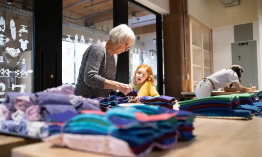 An older woman and a young girl work together to pack a Dignity Kit at MCC's Manitoba office