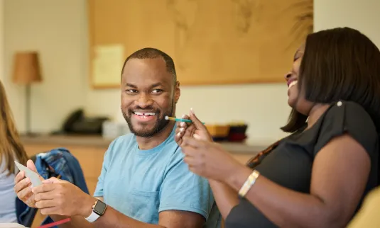 Kojo Kyei on the left laughing while painting, Sarah Njeri on the right