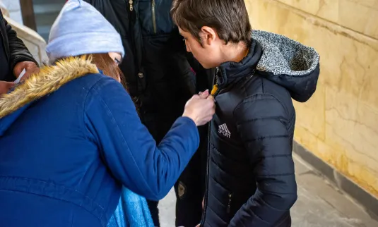 A kid tries on a new coat with assistance from his parent.