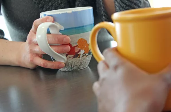 People holding a pair of mugs