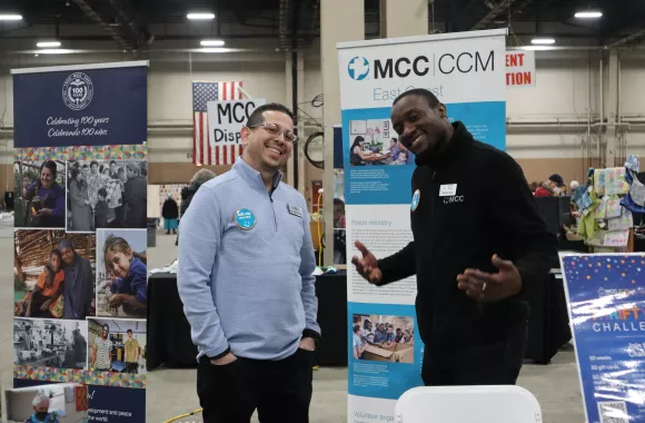 Two men smiling at an MCC booth at a conference