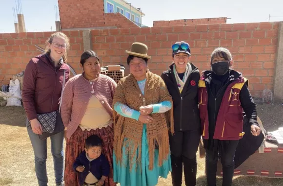 Five adults and one child stand together and smile at the camera