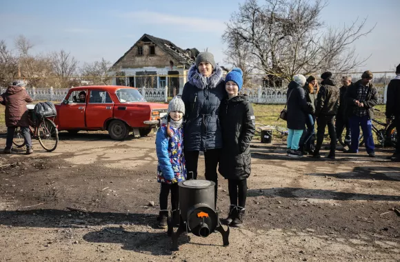 A woman and children in front of a destroyed house in Ukraine