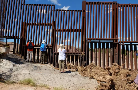 People looking through a border wall
