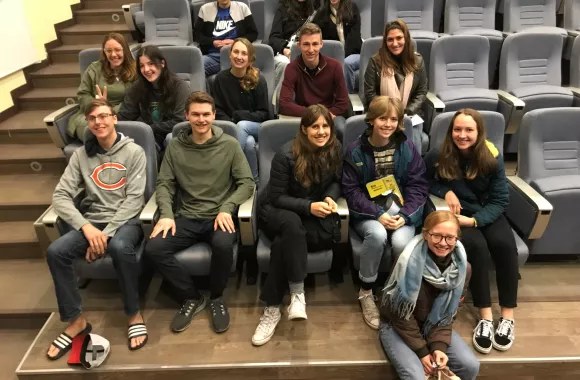 Fourteenth young adults sit in chairs in an auditorium.