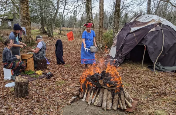 A group of people sitting outside of a sweat lodge