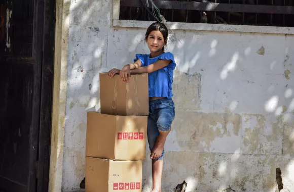 A young girl standing with three boxes of relief supplies